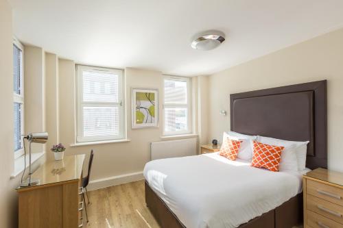 um quarto com uma cama grande com almofadas laranja e branca em House of Fisher - Central House em Camberley