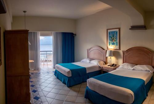 um quarto de hotel com duas camas e uma varanda em El Cozumeleño Beach Resort - All Inclusive em Cozumel