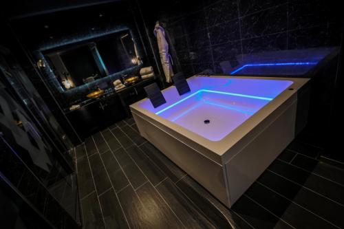 a large bathroom with a tub with blue lighting at H Hotel & SPA - Adults Only in St Julian's