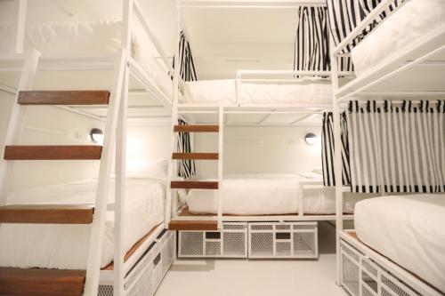 a room with white bunk beds in it at Hostel Lullaby Non-Smoking in Chiang Mai