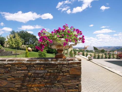a vase filled with pink flowers on a stone wall at Hotel Estalagem Turismo in Bragança