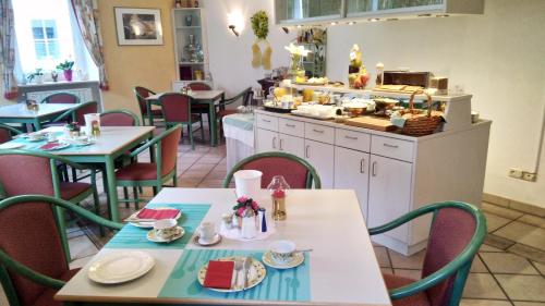 a restaurant with tables and chairs and a kitchen at Haus am Kurpark Hotel Garni in Bad Steben