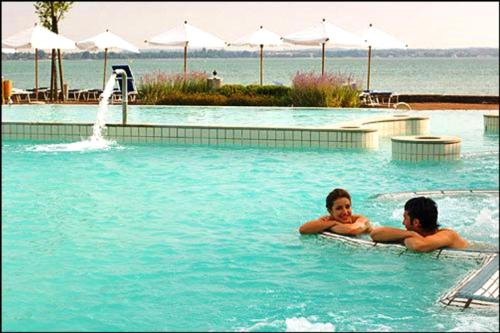 two people are swimming in a swimming pool at Bio Suites PACINOTTI in Bardolino