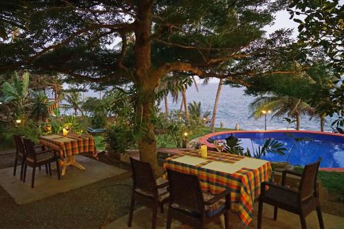 a table and chairs under a tree next to the water at Villa Lucky Star in Tangalle