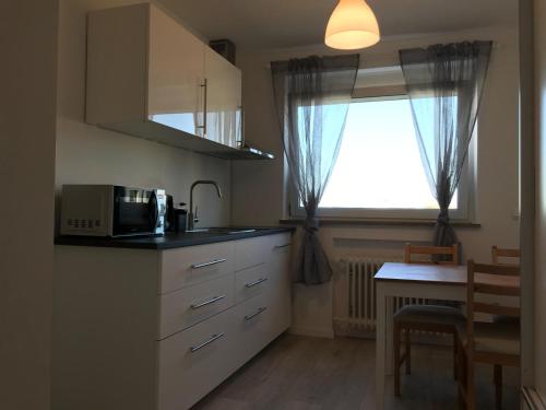 cocina con microondas, mesa y ventana en Pension QMT Reutlingen en Reutlingen