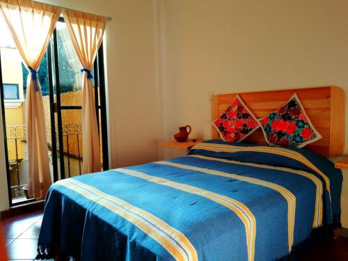 a bedroom with a blue bed with two pillows on it at Casa Gecko in Oaxaca City