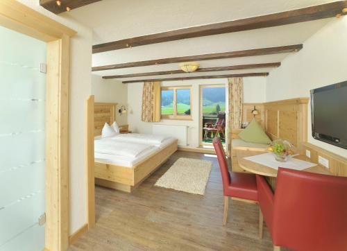 a bedroom with a bed and a desk and a television at Hotel Natur-Landhaus Krone in Maierhöfen