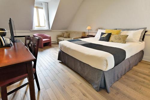 a hotel room with a large bed and a desk at Hotel Cap-aux-Pierres in L'Isle-aux-Coudres