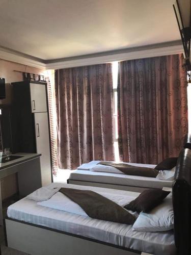 two beds in a bedroom with a window with curtains at Sport Residence in Bacău
