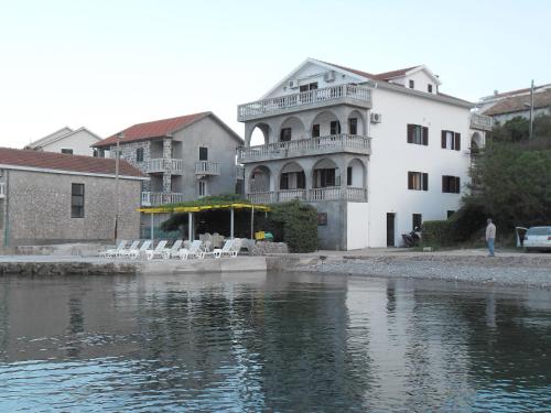 een gebouw naast een waterlichaam met stoelen bij Apartments Petrović in Tivat