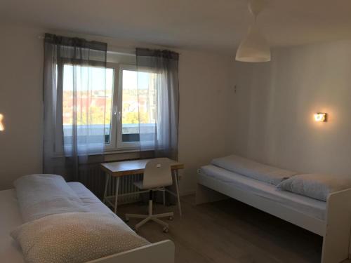 a bedroom with two beds and a desk and a window at Pension QMT Reutlingen in Reutlingen