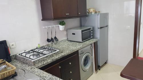 a kitchen with a stove top oven next to a refrigerator at Appartement au Centre de Martil in Martil