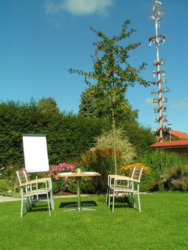 two chairs and a table and a tree in a yard at Hotel Natur-Landhaus Krone in Maierhöfen