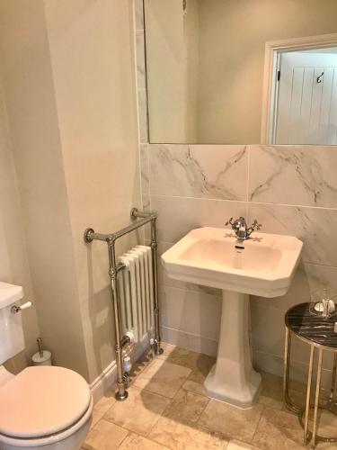 a bathroom with a sink and a toilet and a mirror at The Ormond At Tetbury in Tetbury