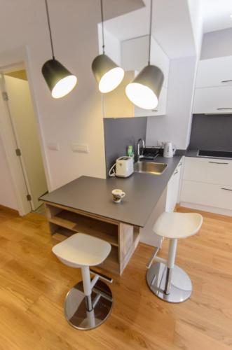 a kitchen with a black counter and two stools at Sava Smart Apartment in Belgrade