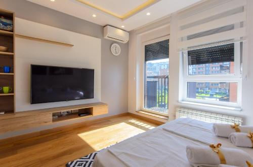 a bedroom with a tv and a bed and two windows at Sava Smart Apartment in Belgrade
