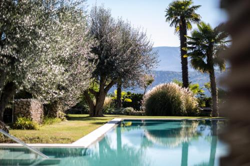 a swimming pool with trees and a mountain in the background at Felderer Boutiquehotel in Caldaro