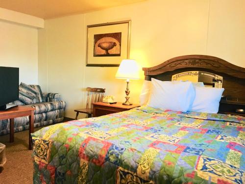 a bedroom with a bed and a chair and a lamp at North Country American Inn in Kalkaska