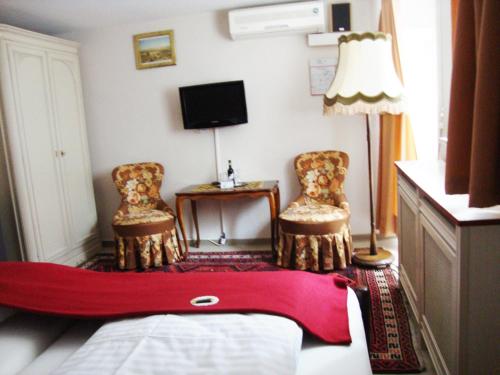 a bedroom with a bed and two chairs and a lamp at Haus Mooren, Hotel Garni in Düsseldorf