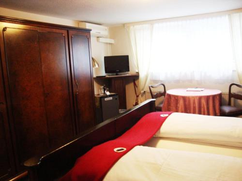 a hotel room with a bed and a cabinet and a table at Haus Mooren, Hotel Garni in Düsseldorf