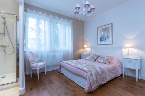 a bedroom with a bed and a window and a chandelier at La Belle Vie Capbreton in Capbreton