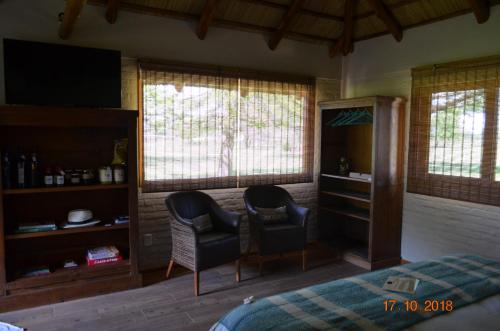 a bedroom with two chairs and a bed and windows at CABAÑA LA TOSCANA in Carmelo