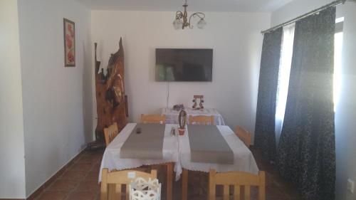 a dining room with a table and chairs and a television at Pensiunea Casa Vanatorului in Oţeleni
