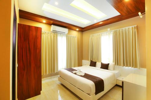 a bedroom with a bed in a room with windows at MAZUS INN in Vythiri