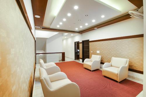 a waiting room with white chairs and a red carpet at MAZUS INN in Vythiri