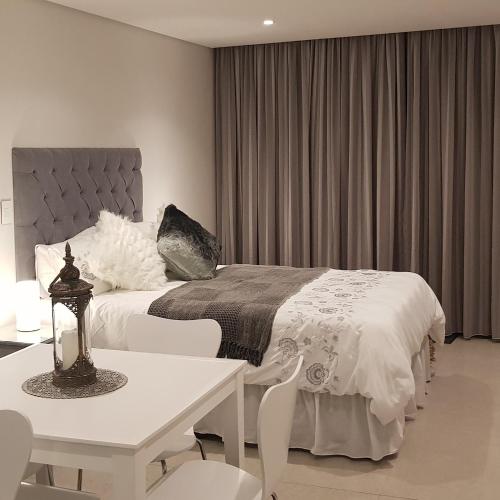 a bedroom with a bed and a table and chairs at No 2 Heleza Blvd Sibaya, Oceandune, Umhlanga Durban in Umdloti