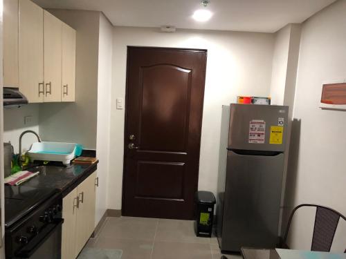a kitchen with a black door and a refrigerator at Baguio Central Apartment by Goshenland in Baguio