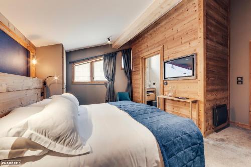 a bedroom with a bed and a flat screen tv at H&ocirc;tel Avancher in Val dʼIs&egrave;re