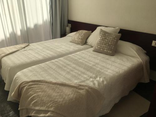 una camera con 2 letti con lenzuola e cuscini bianchi di White House Suite a Los Llanos de Aridane