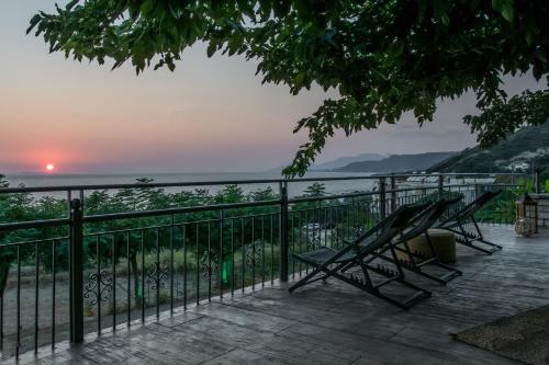 a couple of chairs sitting on a deck watching the sunset at Hotel Agios Thomas in Ligia