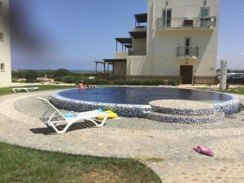 a swimming pool with a chair and a pool at Aphrodite Beachfront Apartment in Ghaziveran