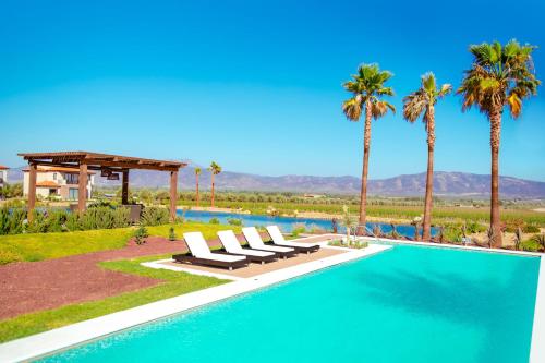 a beach with a pool, chairs, and lawn chairs at El Cielo Resort in Valle de Guadalupe