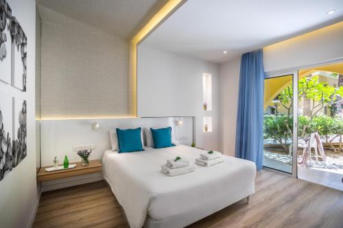 a bedroom with a large white bed with blue pillows at Malama Beach Holiday Village in Protaras