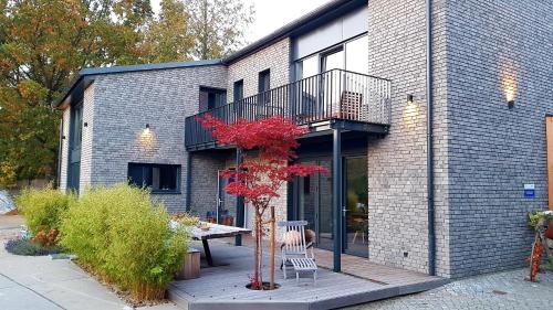 une maison avec un balcon, une table et un arbre dans l'établissement Hey Spreewald Ferienapartments, à Lübben