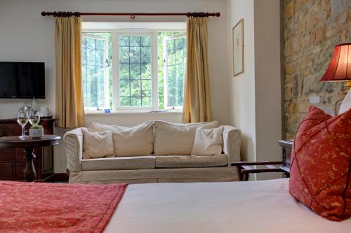 a bedroom with a bed and a couch and a window at The Grange at Oborne in Sherborne