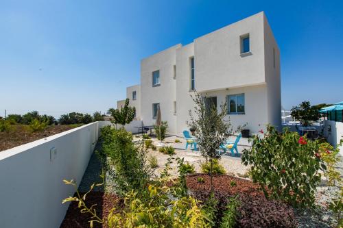a white house with blue chairs in front of it at Blue Diamond Beach Villas in Paphos City