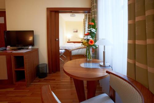 Una habitación con una mesa con un jarrón de flores. en Hotel Penzion Na Hradě en Olomouc