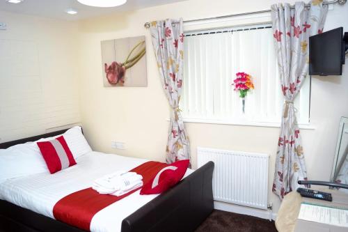 a bedroom with a bed with red pillows and a window at RICHFLO Facility Rentals in Manchester