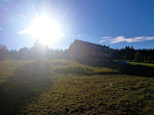 a house in a field with the sun in the sky at Březník Kilián in Kvilda