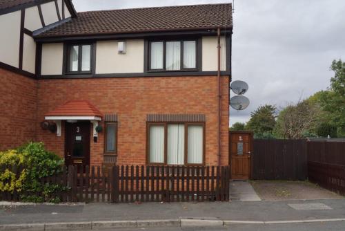 a red brick house with a wooden fence at RICHFLO Facility Rentals in Manchester