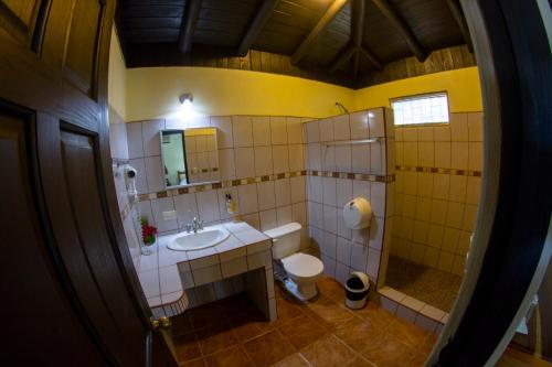 a bathroom with a sink and a toilet and a mirror at Cañon de la Vieja Lodge in Liberia