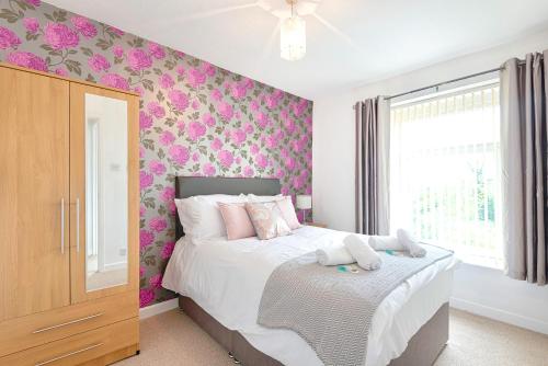 a bedroom with a bed with pink floral wallpaper at The Swans in Swansea