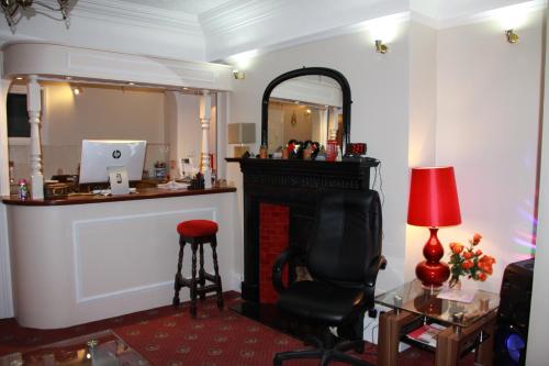 Habitación con chimenea, silla y espejo. en Ambassador Hotel en Brighton & Hove