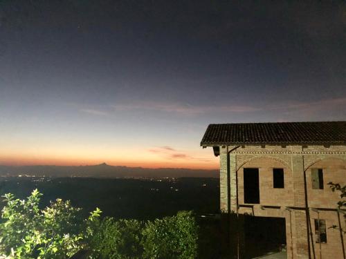 a building with the sunset in the background at Cascina Filipot in Cerretto Langhe