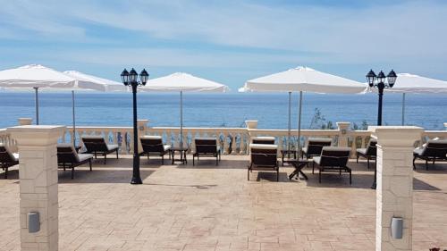 a patio with tables and chairs and umbrellas on the beach at Kostas Beach Apartments in Agios Gordios