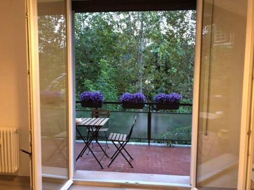 an open sliding glass door with a balcony with purple flowers at Four Rooms in Bologna
